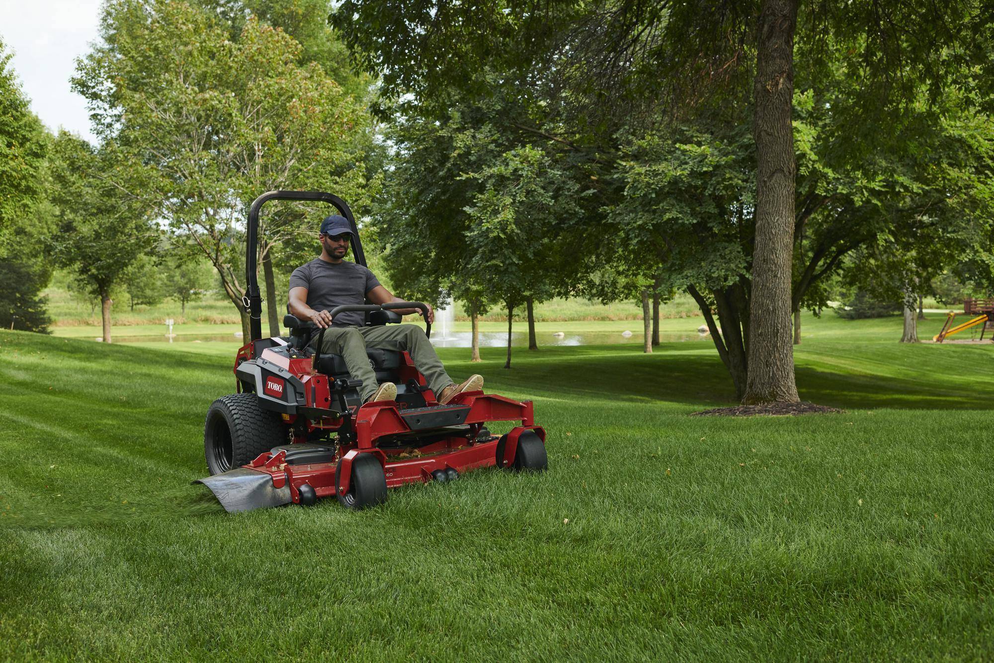 Man operating a red zero-turn lawn mower on a well-manicured lawn, demonstrating dependable power equipment.
