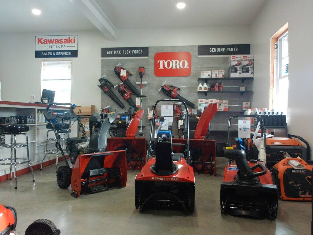 Snowblower display featuring Toro and Kawasaki products, showcasing various models and genuine parts in a retail setting.