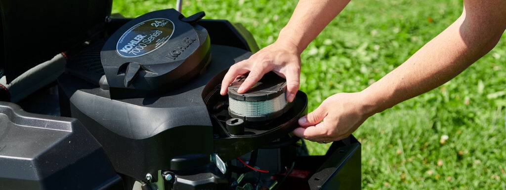 Person inspecting air filter on a Kohler 700 Series engine, emphasizing maintenance for lawn mower performance and troubleshooting.
